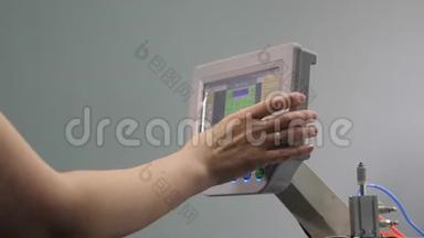 工人正在用平板电脑编程一台数控缝纫机。 操作人员设置数控机床。
